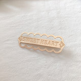 Gold alloy letter clip hair accessory with engraved messages 'SWEET HEART', 'BE MINE', and 'LOVE ME', ideal for weddings or travel gifts in Europe.