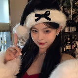 Ladies Christmas Bow Hathat headwear for bank robbers crossword featuring a black tall crown Santa hat with white faux fur trim and a red outfit.